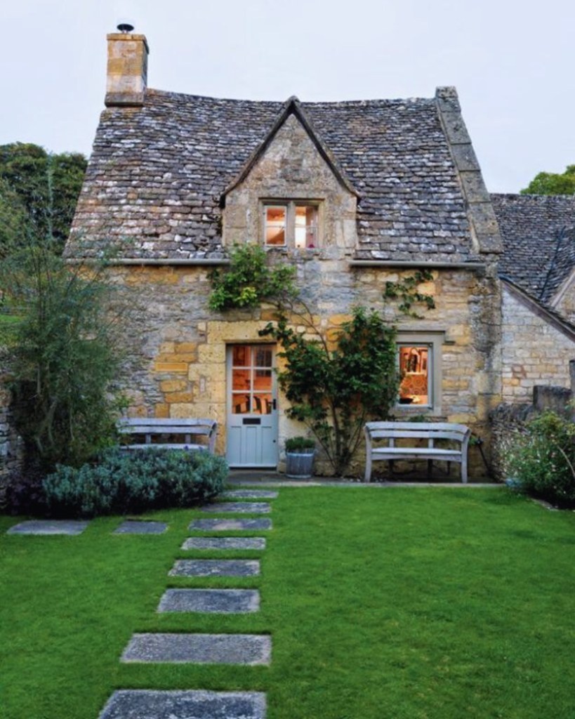 Picture of a natural stone cottage with a green garden and paving steps in the foreground
