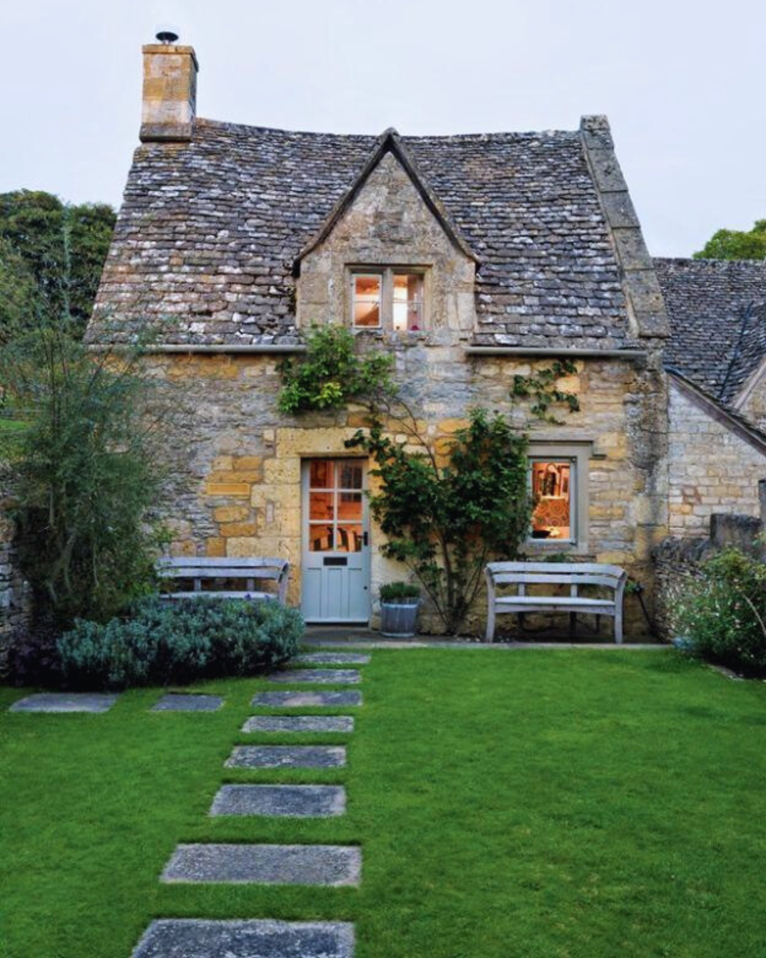 Picture of a natural stone cottage with a green garden and paving steps in the foreground