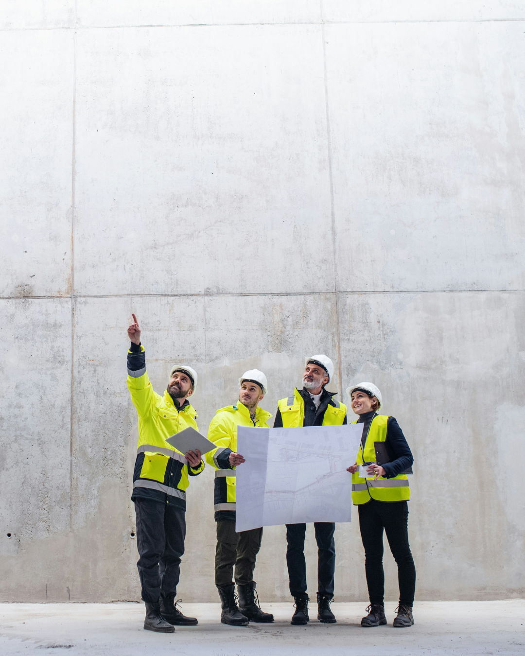 Picture of four people in hard hats and high vis jackets holding drawings on a construction site