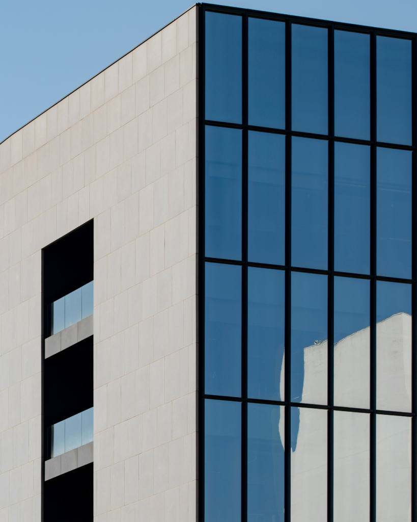 Image of a modern building with curtain glazed front elevation and smooth stone side elevation