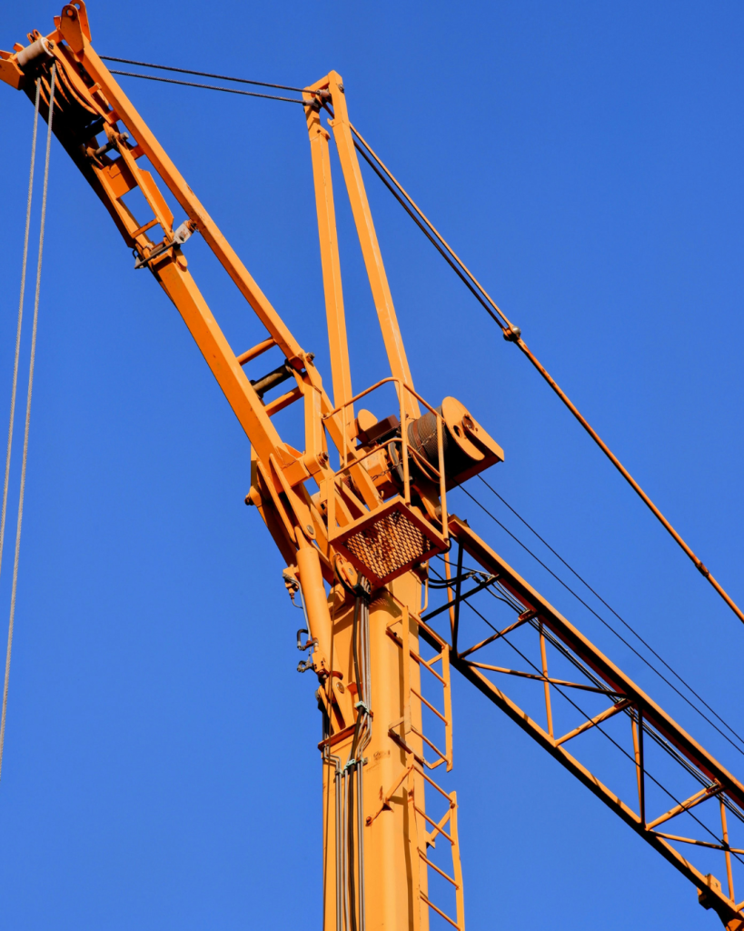 Picture of a yellow construction crane offset against a blue sky